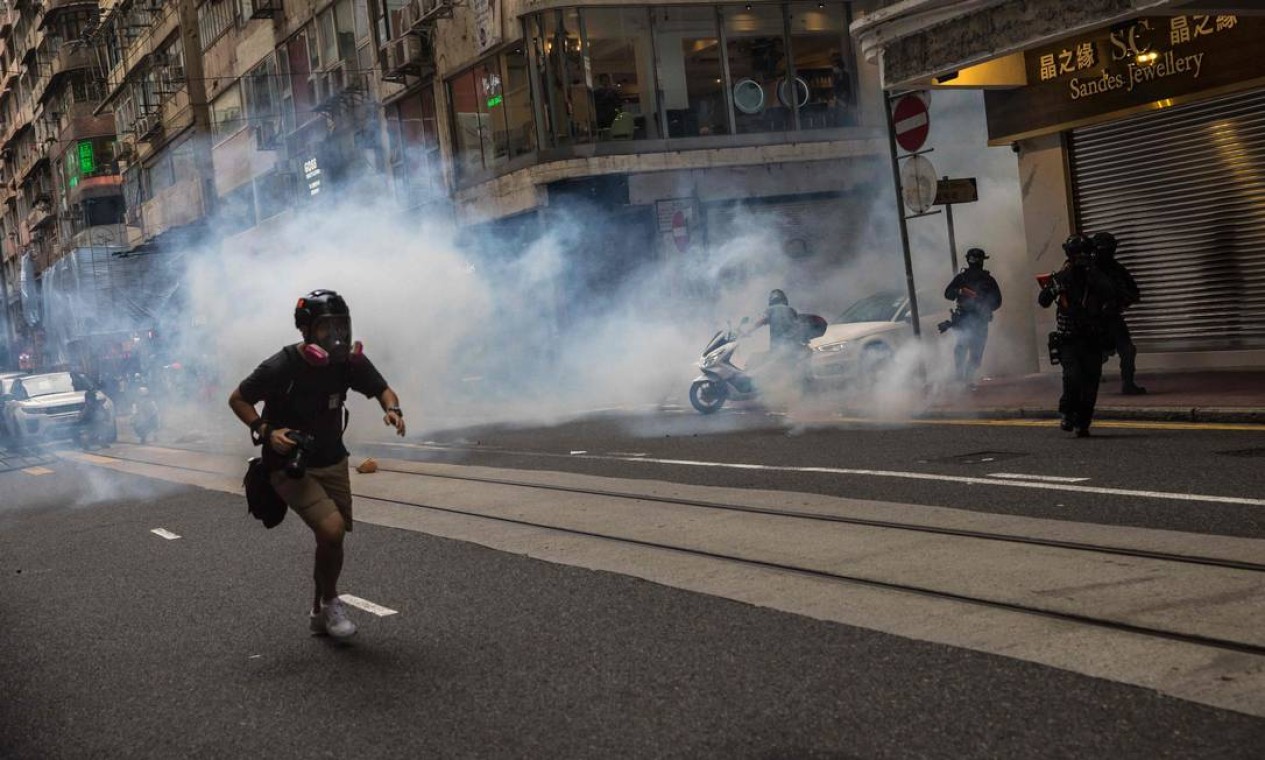 Manifestante foge de gás lacrimogêneo atirado pela polícia para dispersar protesto Foto: DALE DE LA REY / AFP