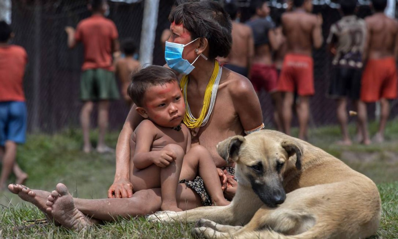 Uma indígena Yanomami usa uma máscara ao lado de seu bebê e um cachorro Foto: NELSON ALMEIDA / AFP