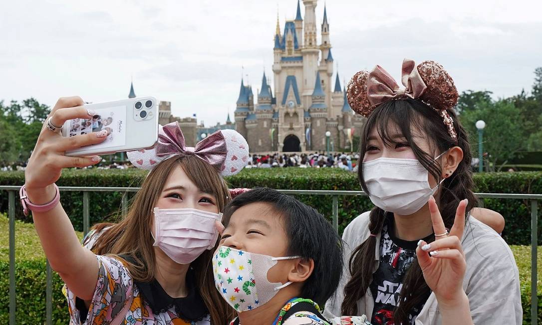 Visitantes posam para uma selfie em frente ao castelo da Disneyland de Tóquio, que reabriu em 1º de julho Foto: STR / AFP