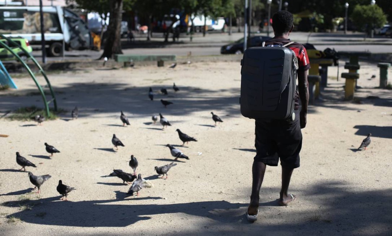 Com pertences guardados em uma mala de viagem, homem em situação de rua caminha por rua na Glória Foto: Pedro Teixeira / Agência O Globo
