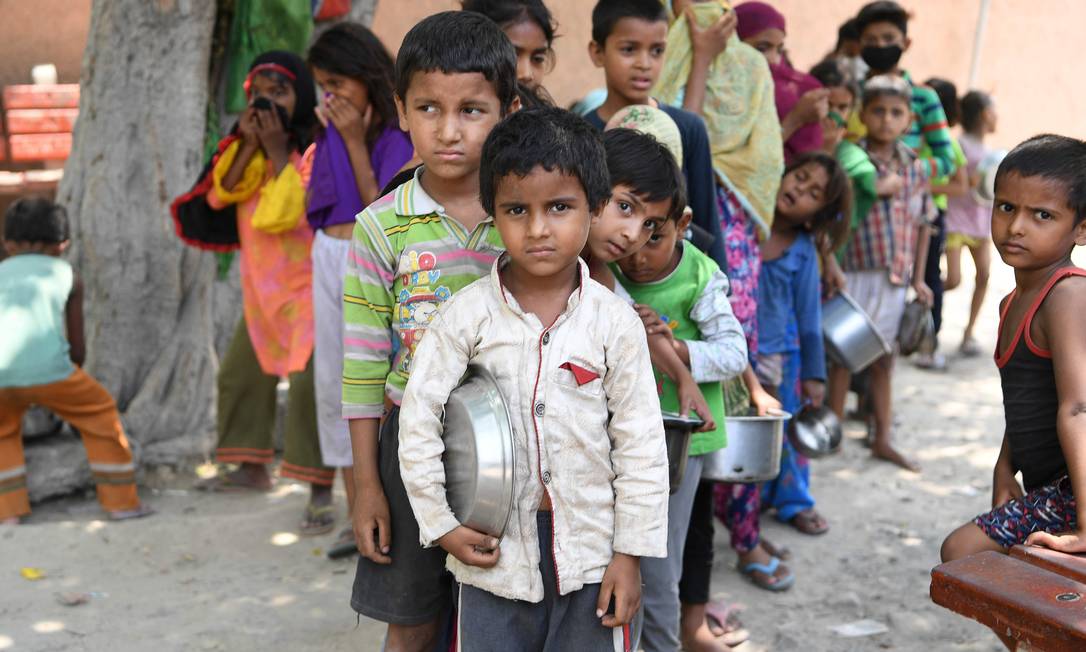 Crianças de uma favela em Nova Délhi, na Índia, fazem fila para receber comida: pandemia aprofundou as desigualdades sociais em todo o mundo Foto: PRAKASH SINGH / AFP