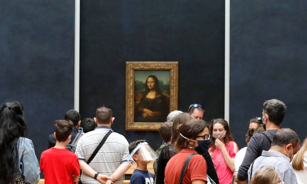 Com máscaras de proteção, como manda o protocolo, visitantes observam o famoso retrato "Mona Lisa", de Leonardo da Vinci, no Museu do Louvre, em Paris, em seu primeiro dia de reabertura desde que fechou as portas por causa da pandemia de Covid-19 Foto: FRANCOIS GUILLOT / AFP