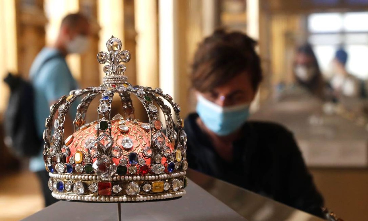 Visitante observa a Coroa de Luís XV, no Museu do Louvre, em Paris. Crise do coronavírus já causou "mais de 40 milhões de euros em perdas" no Louvre, segundo o presidente e diretor, Jean-Luc Martínez Foto: FRANCOIS GUILLOT / AFP