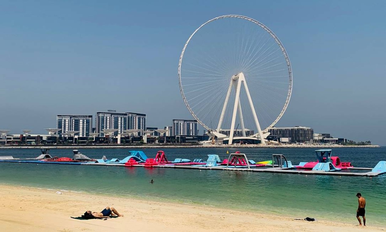 Banhistas tomam sol na praia da Marina de Dubai, perto da roda-gigante Ain Dubai Ferris Wheel Foto: GIUSEPPE CACACE / AFP
