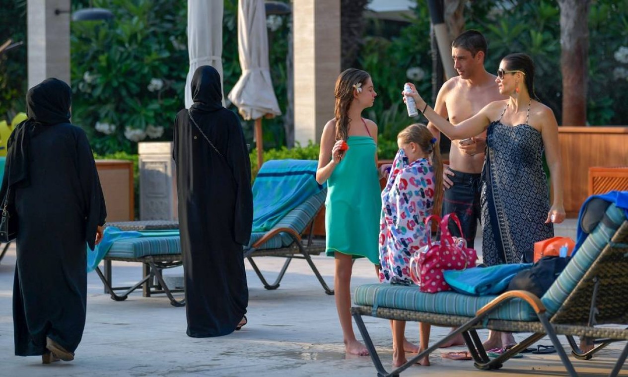 Hóspedes, vestindo roupas de banho ou trajes tradicionais, se encotram na piscina do Al Naseem, um dos hotéis de Dubai que reabriram as portas para os visitantes internacionais Foto: KARIM SAHIB / AFP