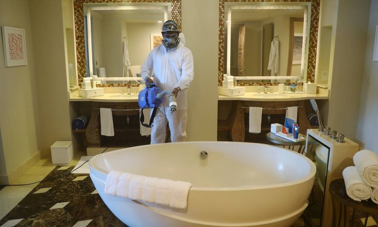Usando uma roupa especial contra o coronavírus, funcionário desinfeta uma das suítes do hotel Atlantis The Palm, em Dubai Foto: AHMED JADALLAH / REUTERS