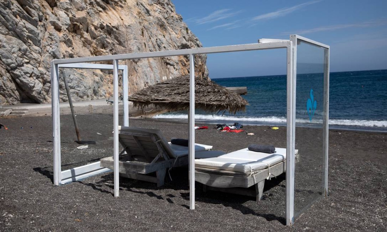 Uma construção com proteção de acrílico cerca espreguiçadeiras na praia de Perissa, na ilha de Santorini, na Grécia Foto: Alkis Konstantinidis / REUTERS