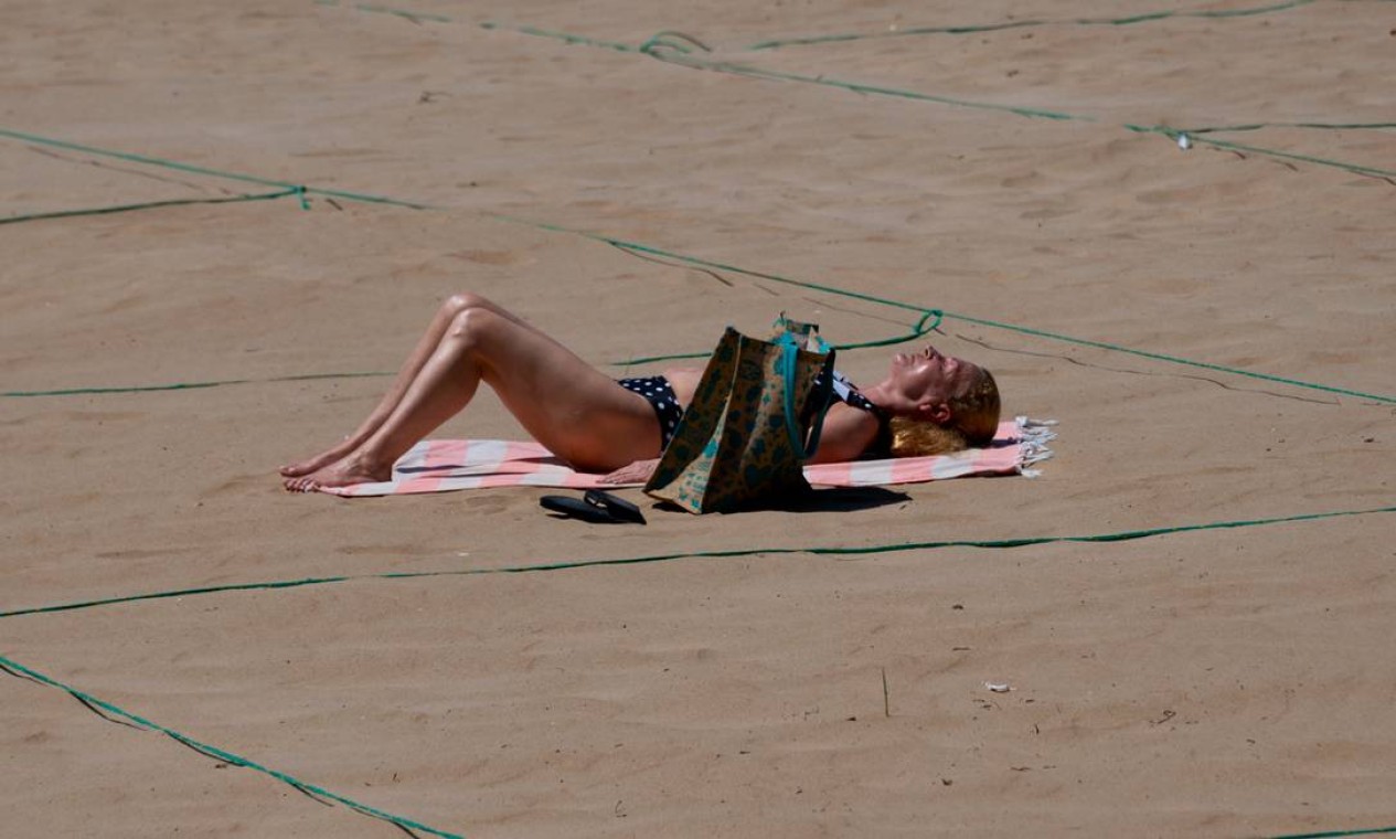 Cordas esticadas na areia definem áreas de distanciamento na praia de Poniente, em Benidorm, na Espanha Foto: JOSE JORDAN / AFP