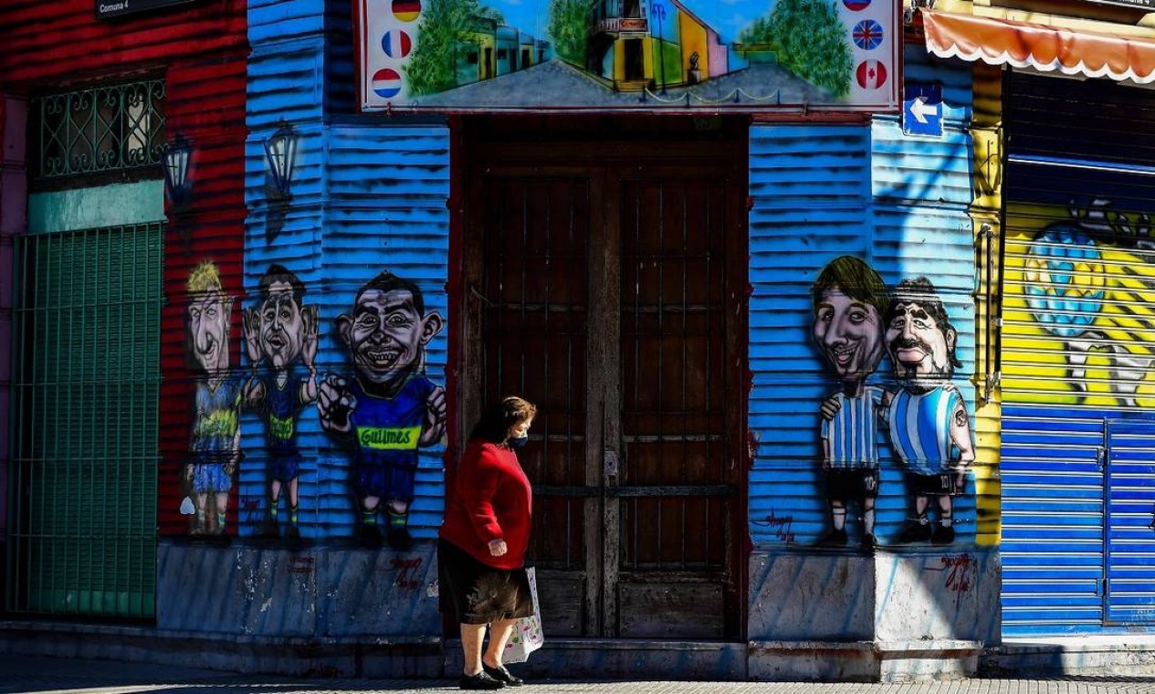 Mulher passa em frente a uma loja fechada no bairro de La Boca, em Buenos Aires Foto: RONALDO SCHEMIDT / AFP