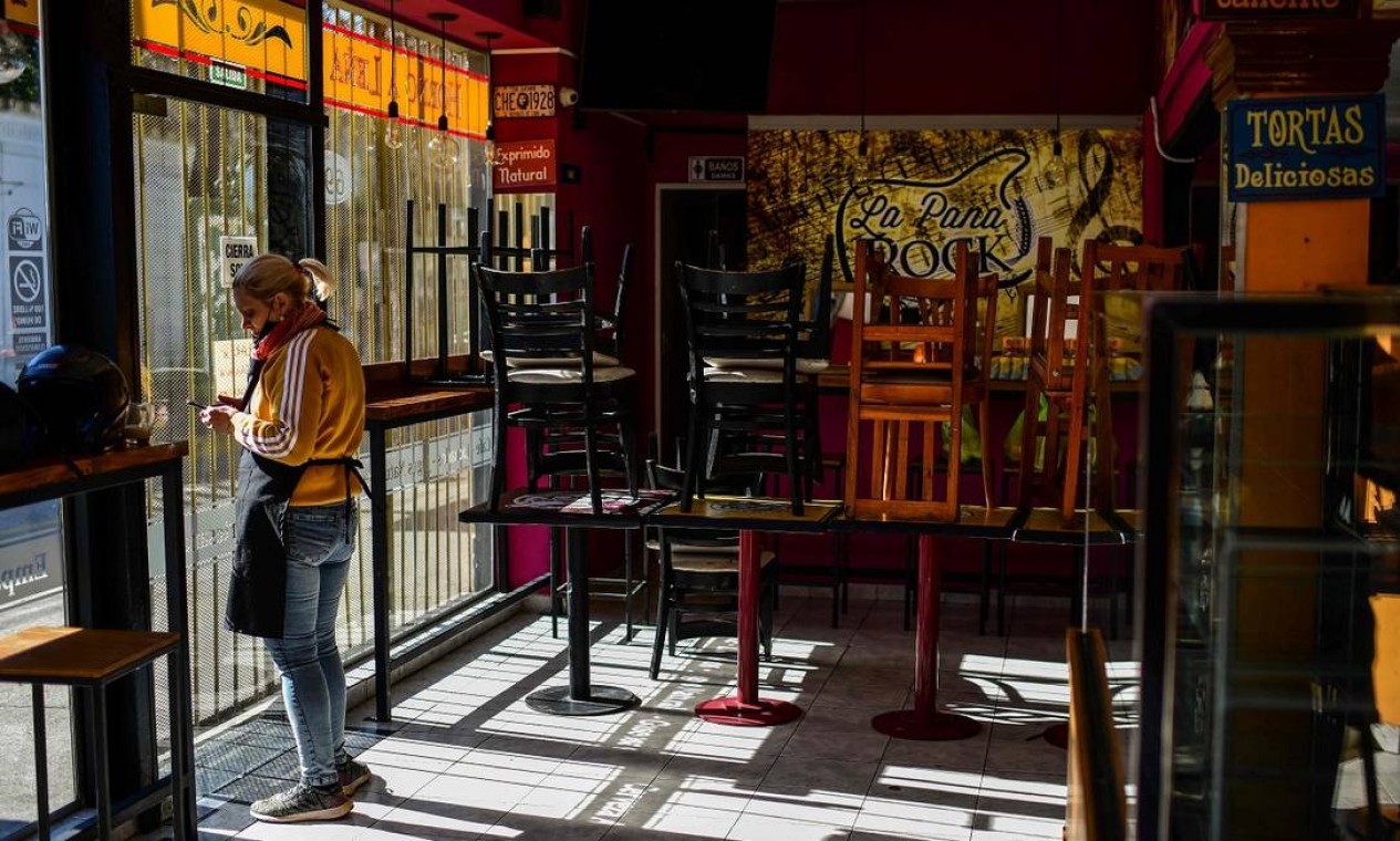 Funcionária de um restaurante vazio no bairro de La Boca, em Buenos Aires Foto: RONALDO SCHEMIDT / AFP