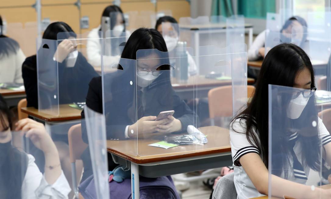 Escola de ensino médio instalou escudos de plástico em cada mesa para evitar contágio do coronavírus Foto: YONHAP / Reuters
