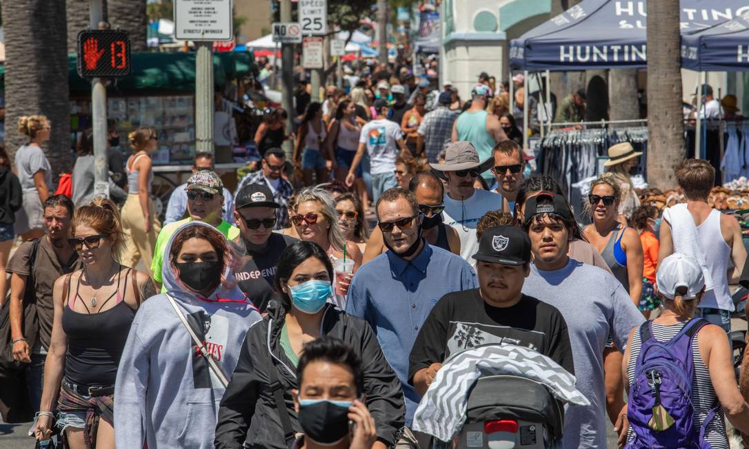 Pessoas andam pelas ruas da cidade de Huntington Beach, na Califórnia Foto: APU GOMES / AFP