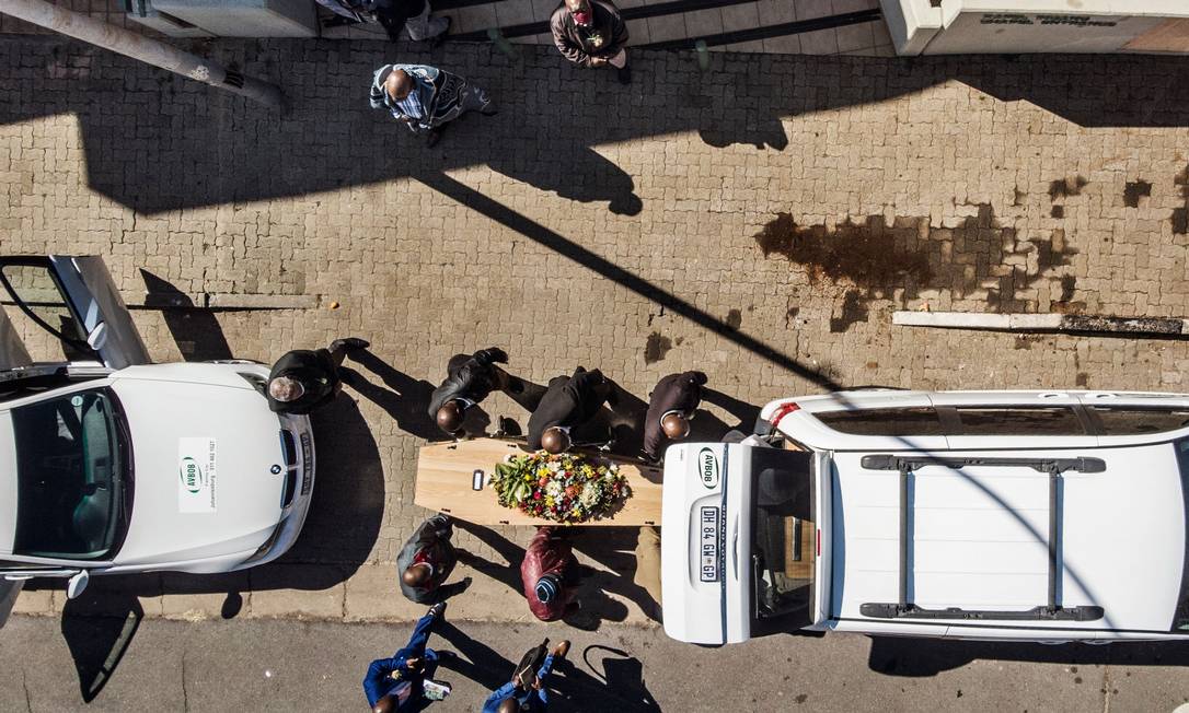 Parentes e funcionários de funerária carregam caixão de vítima da Covid-19 em Johannesburgo, na África do Sul, no último domingo (26); país é o quinto mais afetado pelo coronavírus no mundo Foto: MARCO LONGARI / AFP
