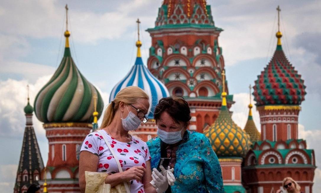 Mulheres usam máscara diante da Catedral de São Basílio Foto: YURI KADOBNOV / AFP