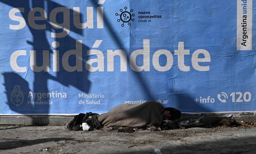 Em Buenos Aires, homem dorme na rua em frente a um cartaz de alerta sobre o coronavírus: ainda que a Argentina tenha menos casos e mortes que vizinhos, flexibilização da quarentena aumentou contágios Foto: JUAN MABROMATA / AFP/24-07-2020