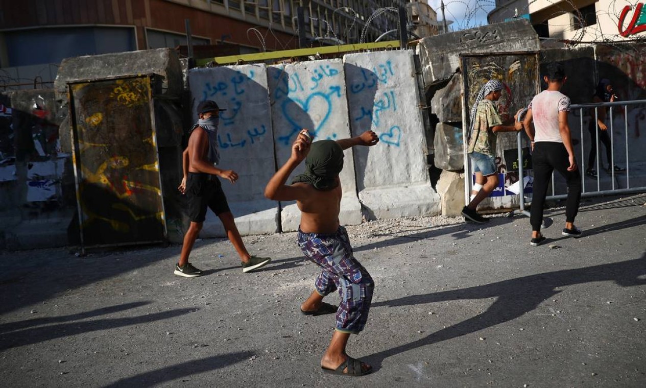 Jovem atira pedra durante protesto, em Beirute, na área destruída pela explosão da última terça-feira (4) Foto: HANNAH MCKAY / REUTERS