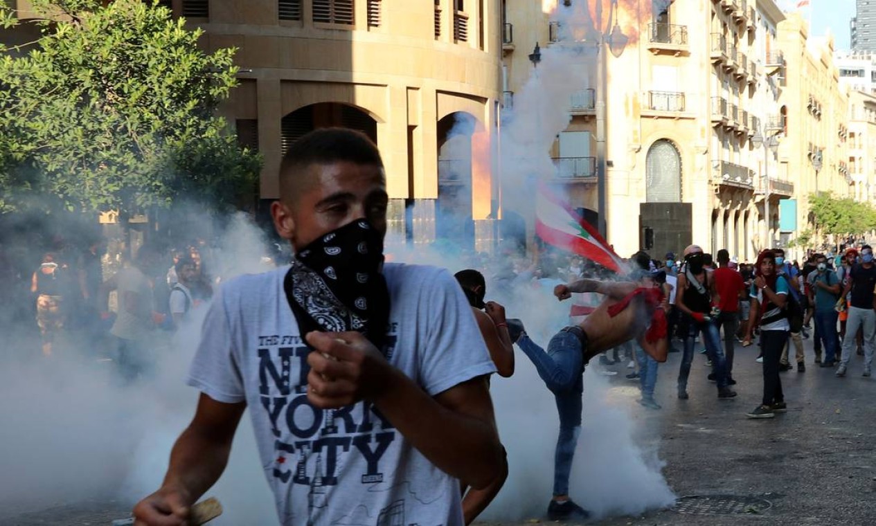 Manifestantes fogem do gás lacrimogêneo disparado pela polícia para dispersar manifestação, em Beirute Foto: ALKIS KONSTANTINIDIS / REUTERS