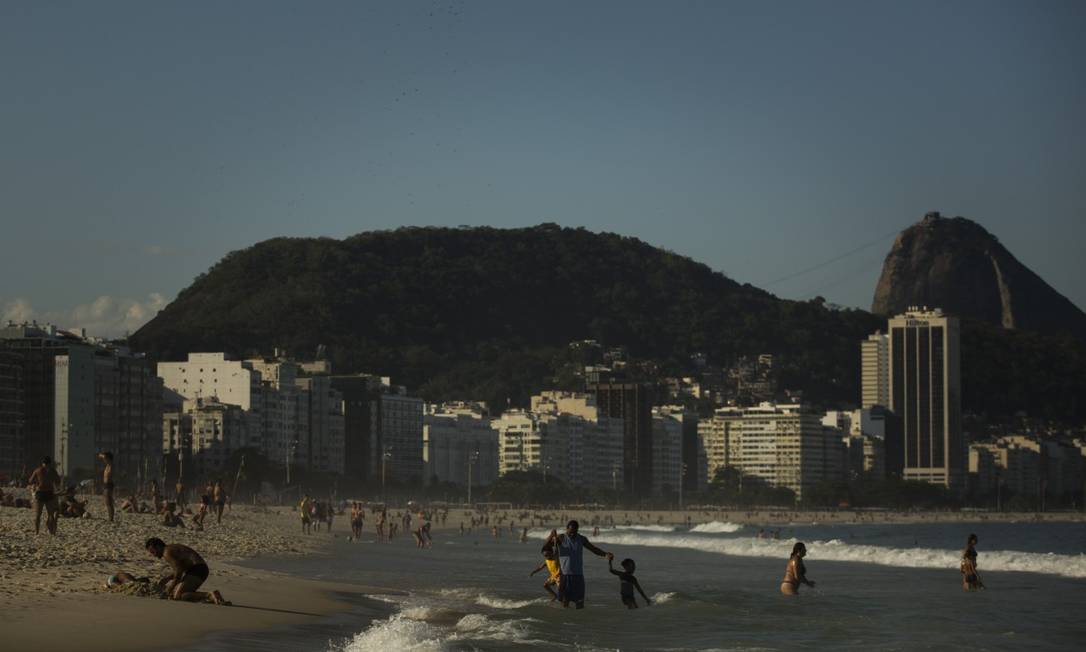 Banhistas no fim de tarde ensolarado, na Praia de Copacabana Foto: Guito Moreto / Agência O Globo