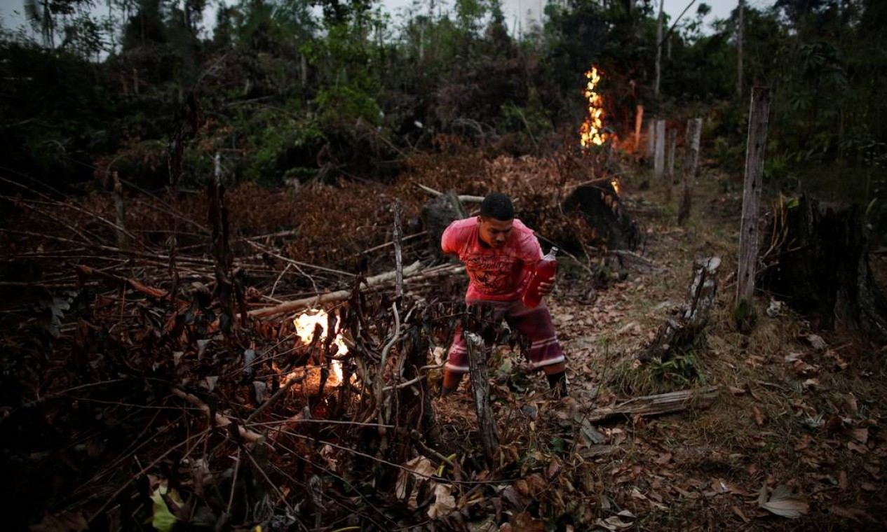 Voluntário acende uma fogueira para criar um aceiro para impedir o progresso de um incêndio iniciado por agricultores que limpam uma área da selva amazônica, em Apuí, no Amazonas Foto: UESLEI MARCELINO / REUTERS
