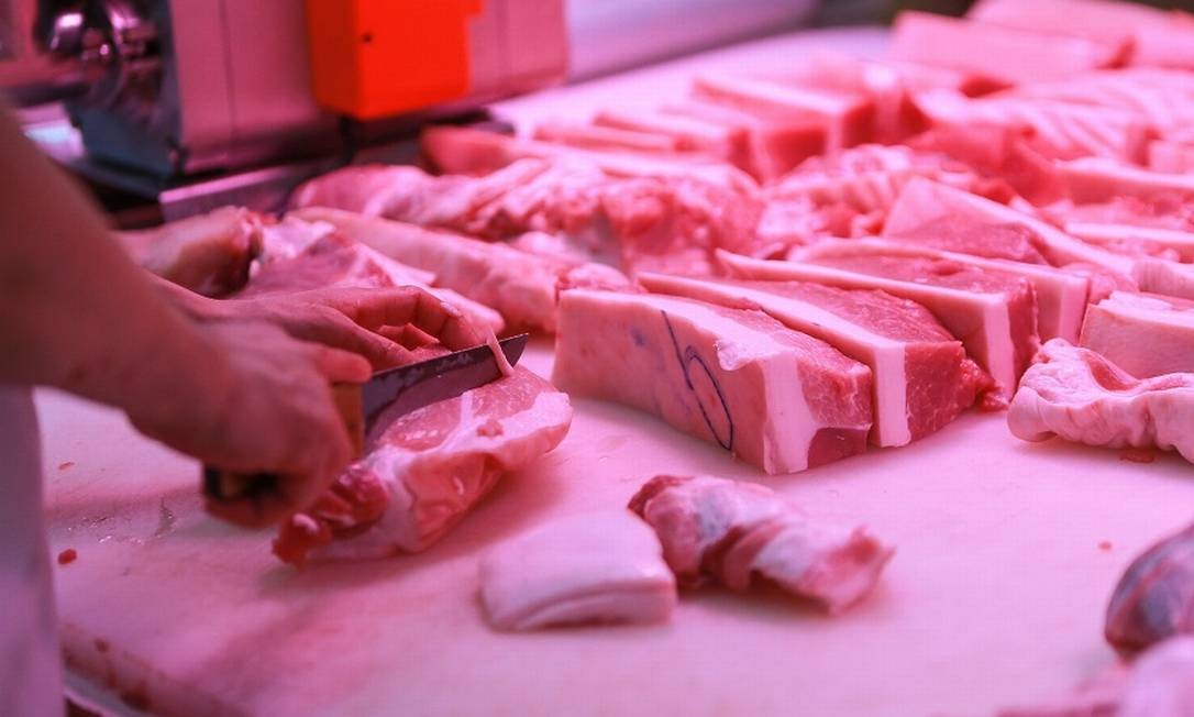 Açougueiro fatia carne em Shenyiang, na China: país asiático preocupado com contaminação do produto pelo vírus. Foto: STR / AFP