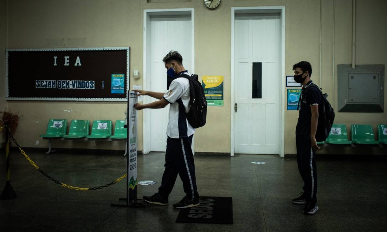 Alunos utilizam um totem com dispensador de álcool em gel, localizado no salão de entrada do colégio, para higienizar as mãos antes do início das aulas Foto: Raphael Alves / Agência O Globo