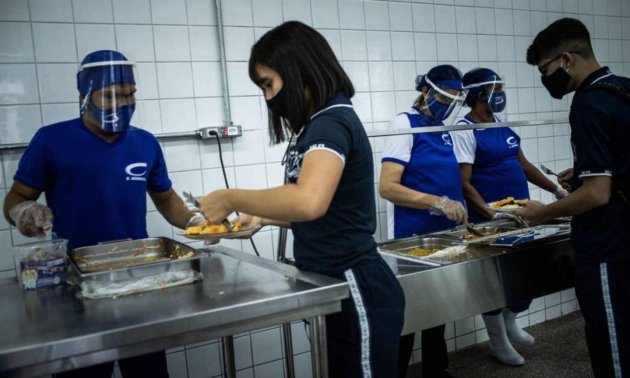 No refeitório, alunos se servem ainda de máscara, com auxílio de funcionários que também utilizam a proteção Foto: Raphael Alves / Agência O Globo