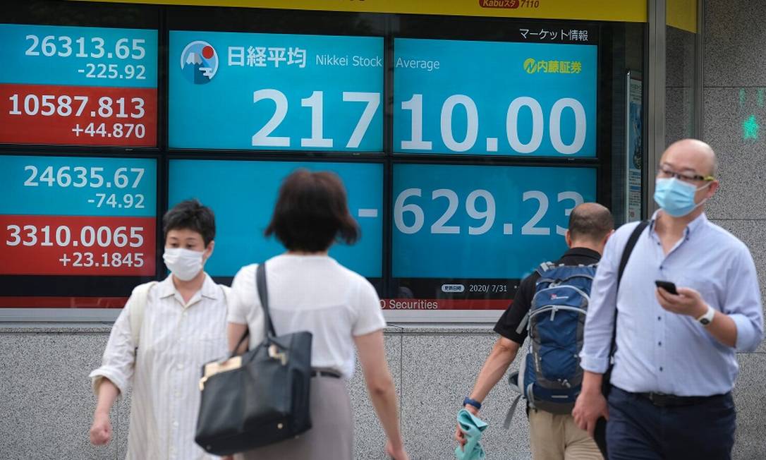 Pedestres passam por painéis da Bolsa de Tóquio: queda histórica no PIB com pandemia Foto: KAZUHIRO NOGI / AFP