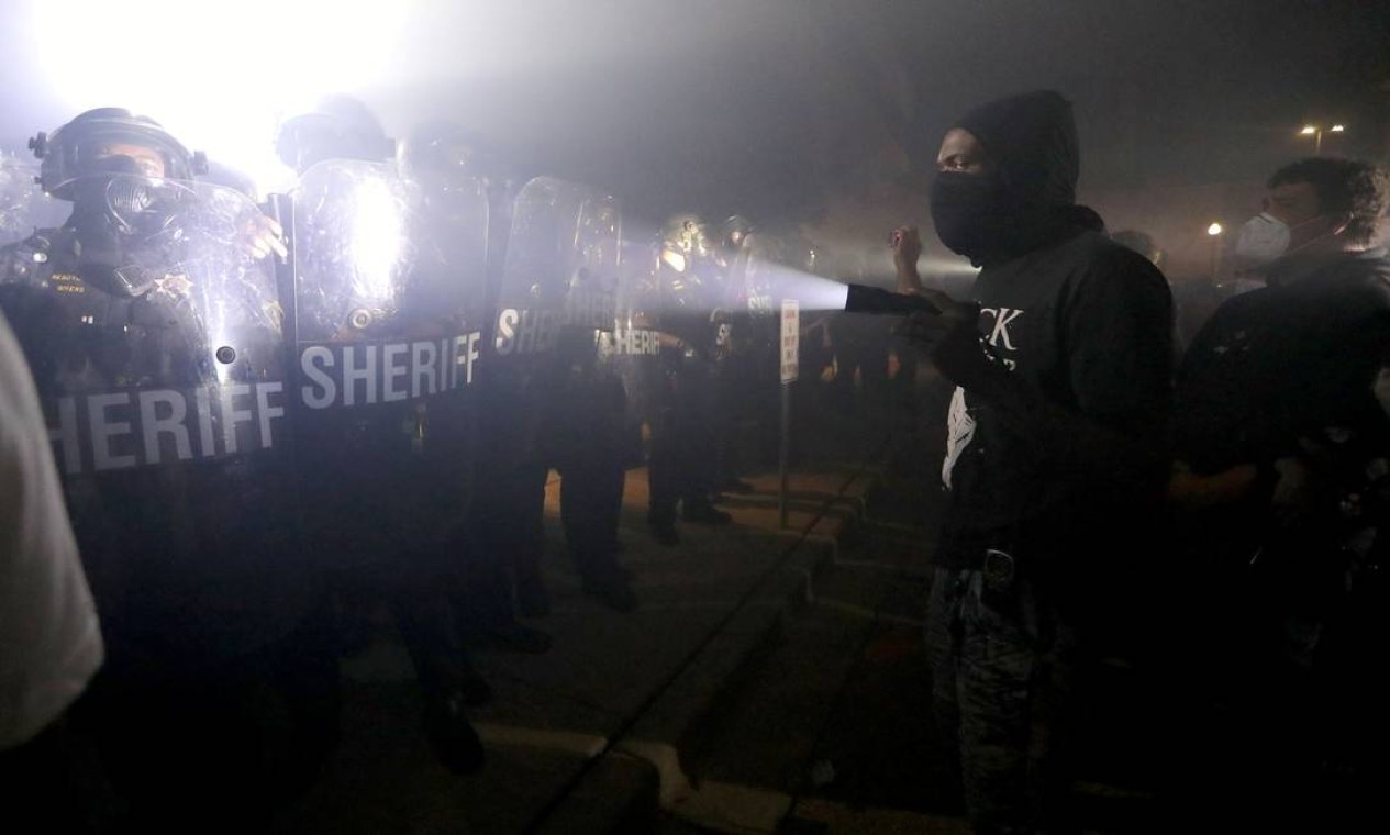 Um manifestante aponta uma lanterna na direção da tropa de segurança durante protesto contra a ação de policiais, que respondiam a um "incidente doméstico" Foto: Mike De Sisti / VIA REUTERS