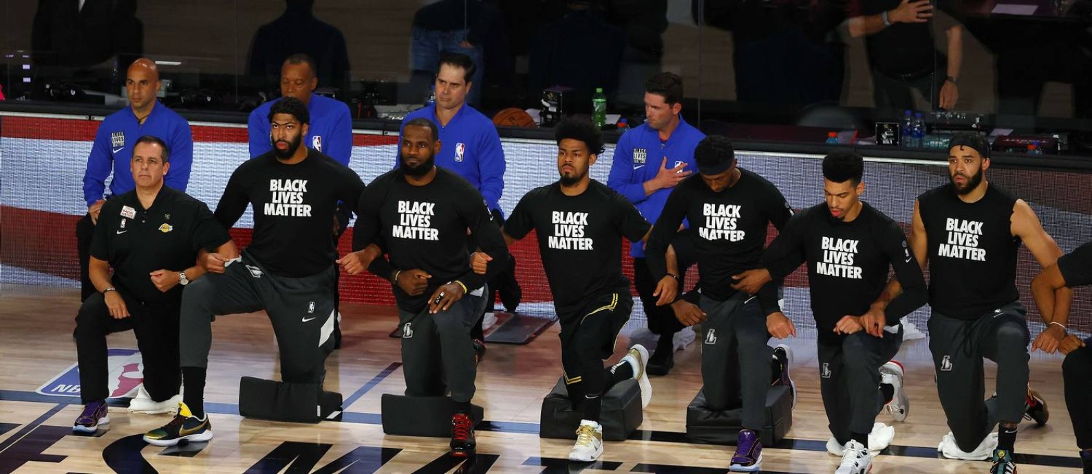 Jogadores do Los Angeles Lakers ajoelhados em protesto durante o hino americano Foto: Kevin C. Cox / AFP