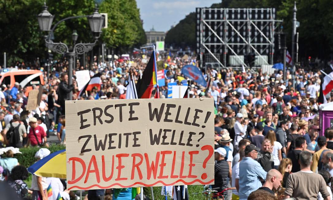 Manifestantes carregam cartaz que diz "Primeira onda! Segunda onda! Onda permanente?" em protesto em Berlim Foto: JOHN MACDOUGALL / AFP/29-08-2020