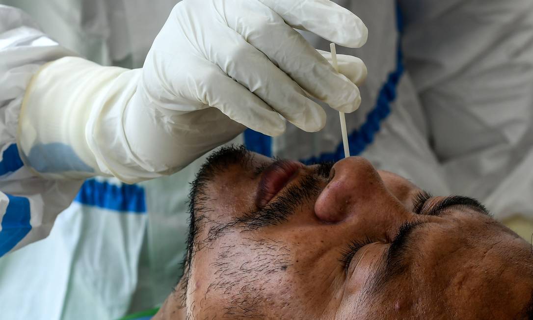 Profissional de saúde coleta amostra para teste que diagnostica o novo coronavírus Foto: PRAKASH MATHEMA / AFP