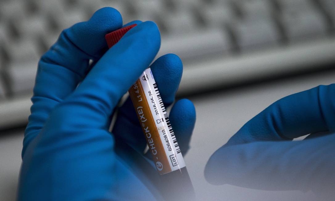 Funcionário de laboratório segura um frasco com teste de esteróides Foto: Alexander Zemlianichenko / AFP