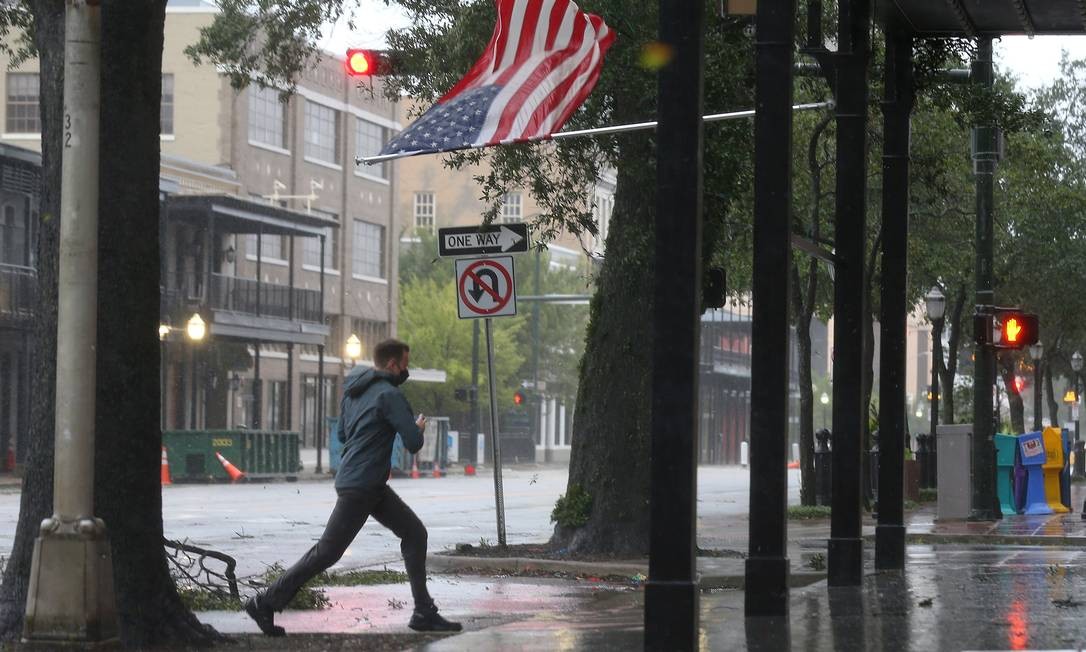 Um homem passa uma bandeira americana durante o furacão Sally em Mobile, Alabama.  Foto: JONATHAN BACHMAN / REUTERS