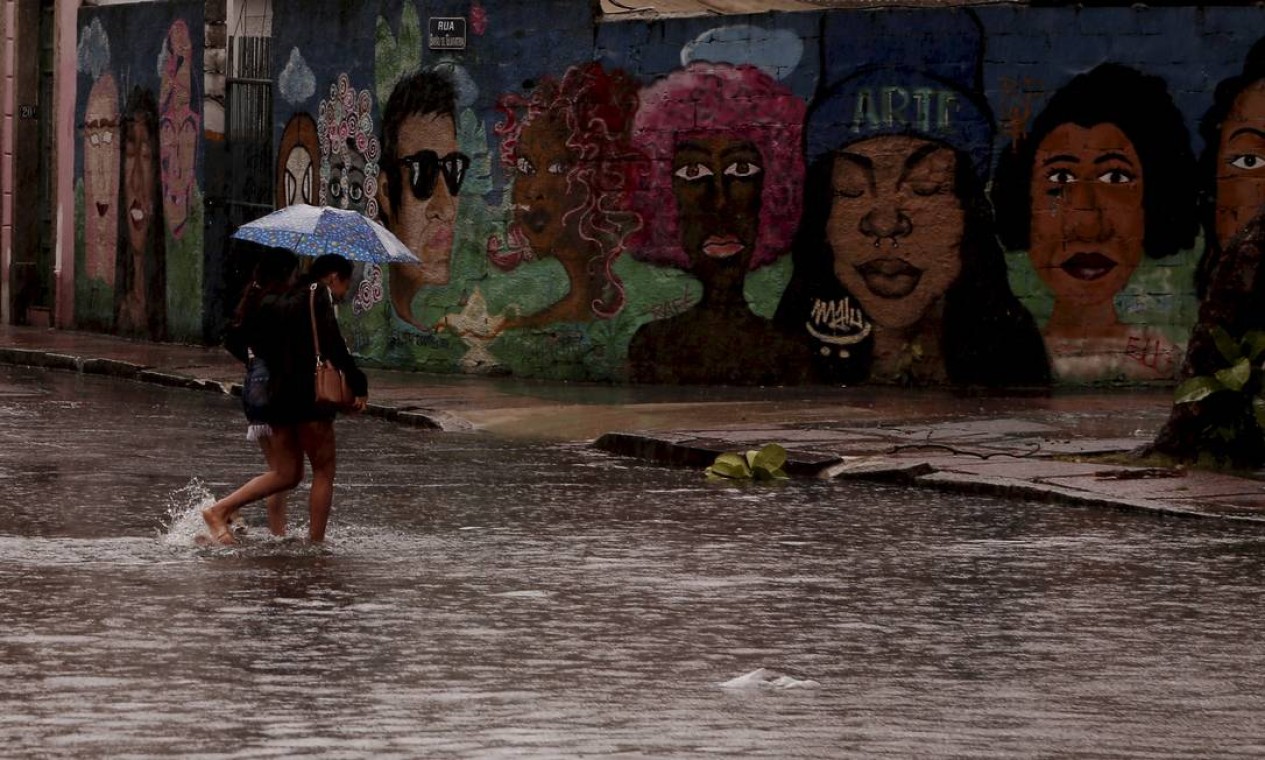 Duas mulheres atravessam uma rua alagada na Glória na tarde desta terça. Após manhã com chuvas variando de fraca a moderada, a tarde no Rio é de chuva forte em pontos isolados Foto: Gabriel Monteiro / Agência O Globo