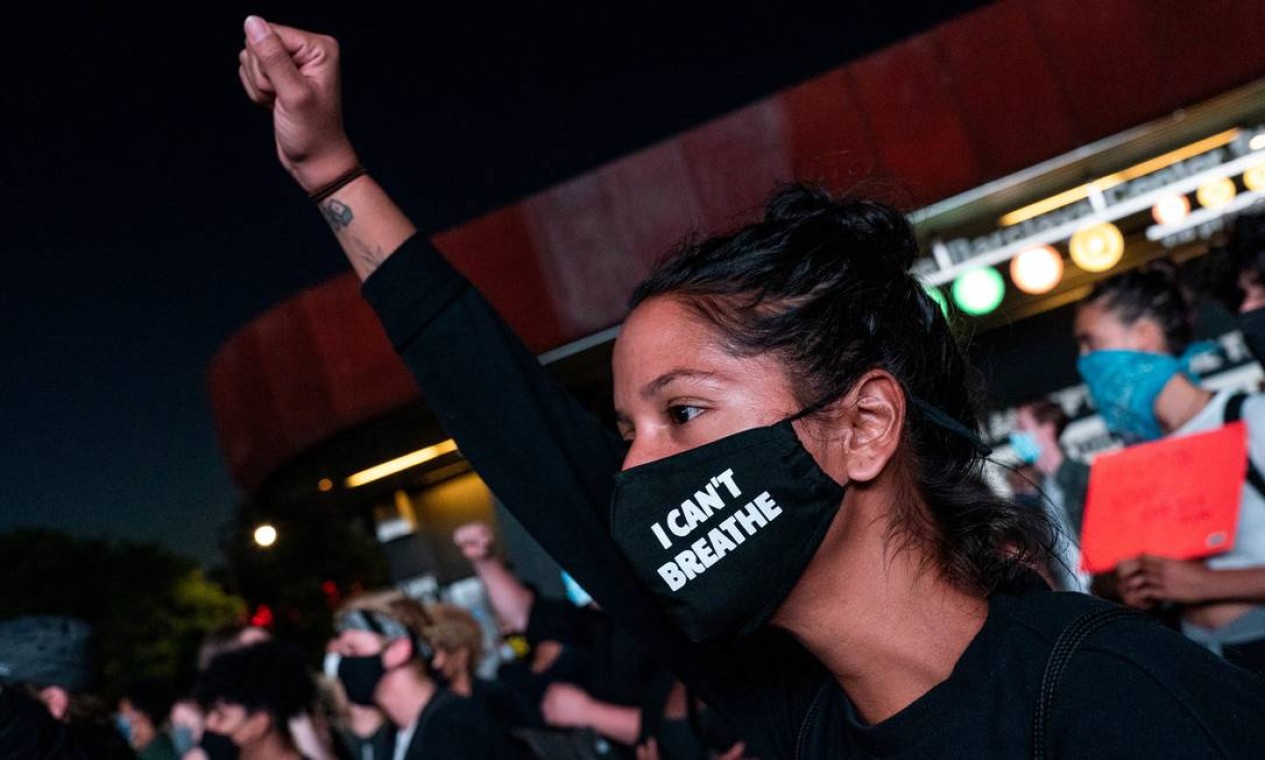 Mulher usando máscara de proteção ergue punho cerrado em protesto no Brooklyn, em Nova Iorque. A frase estampada foi dita 11 vezes por George Floyd, enquanto era sufocado por policiais até a morte, em Minneapolis Foto: JEENAH MOON / REUTERS
