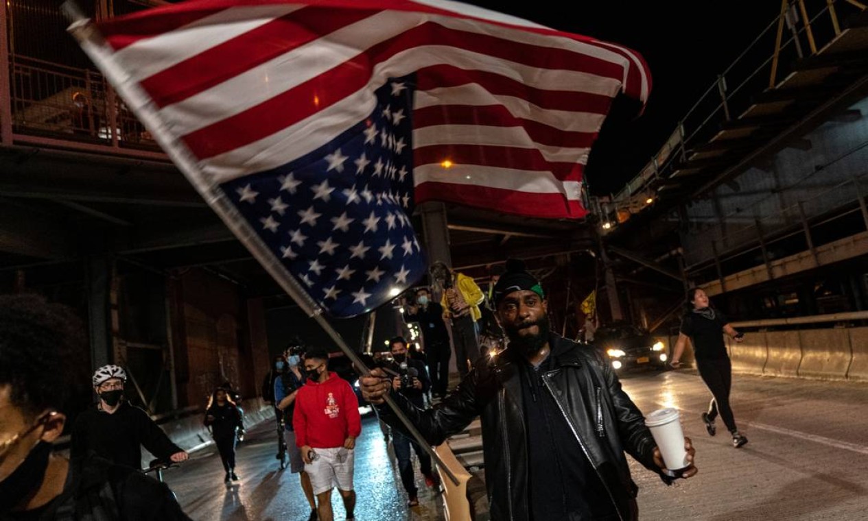 Homem carrega bandeira dos EUA de ponta-cabeça em protesto no Brooklyn, em Nova Iorque Foto: JEENAH MOON / REUTERS