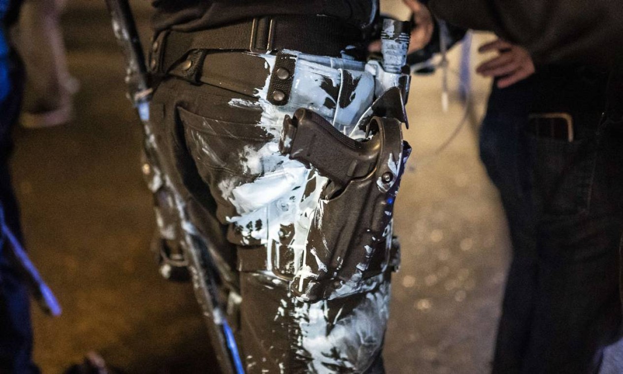 Tinta lançada por manifestantes atinge policial de Portland durante protestos Foto: Nathan Howard / AFP