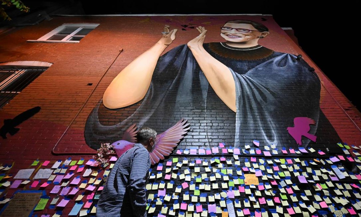 Homem passa diante de mensagens de agradecimento e gratidão gravadas em um mural memorial à falecida juíza da Suprema Corte Ruth Bader Ginsburg, no centro de Washington Foto: ANDREW CABALLERO-REYNOLDS / AFP