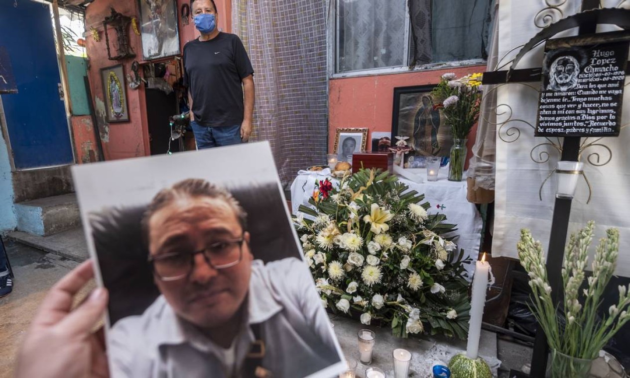 Um parente mostra uma foto do mexicano Hugo Lopez Camacho, que morreu pela COVID-19, durante uma missa após sua morte, na Cidade do México Foto: PEDRO PARDO / AFP
