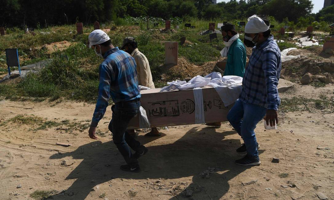 Parentes e coveiros levam o corpo de uma vítima da Covid-19 em Nova Délhi, na Índia Foto: SAJJAD HUSSAIN / AFP