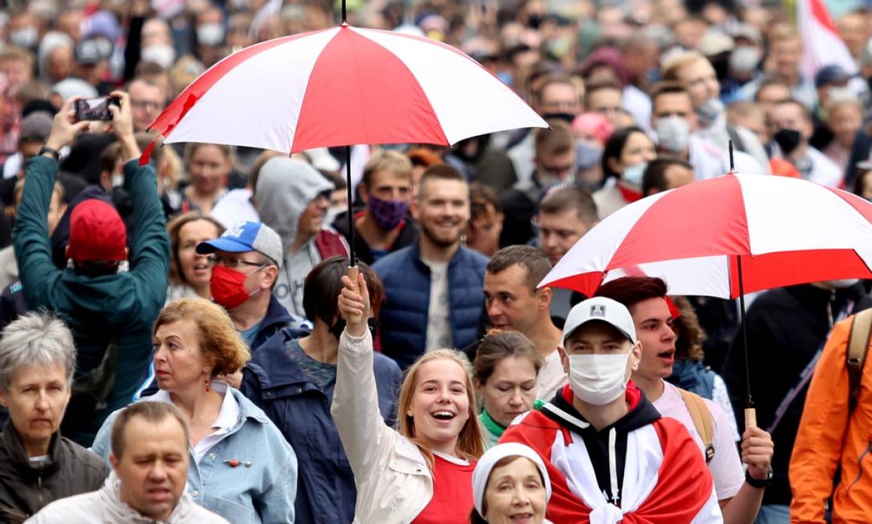 Carregando guarda-chuvas, manifestantes marcham sob chuva pelas ruas de Minsk Foto: AFP