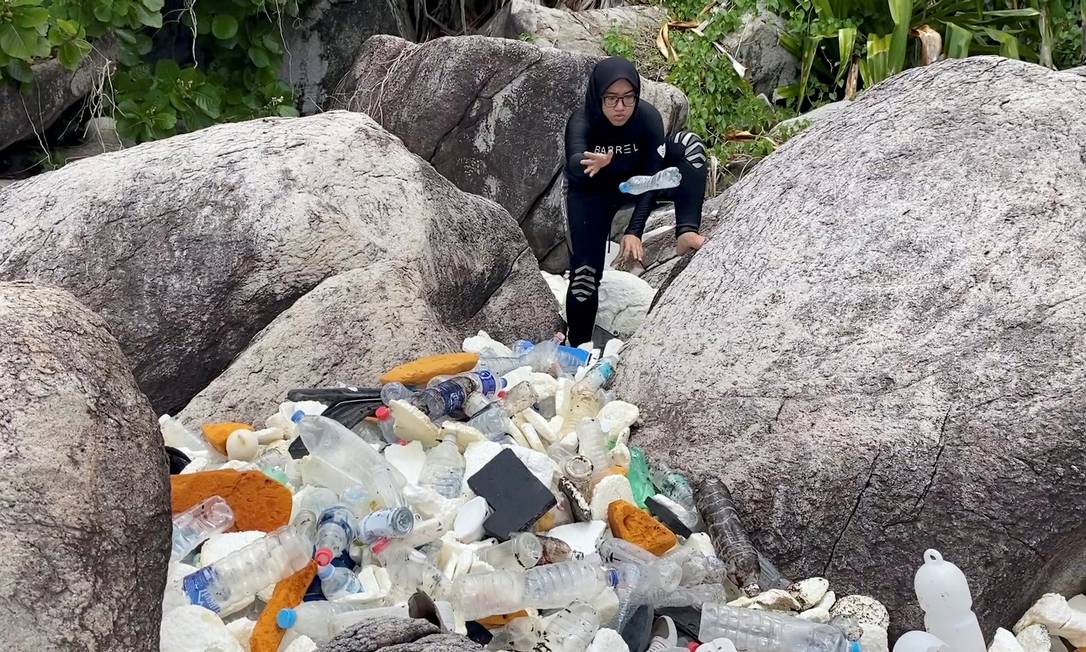 Mulher recolhe garrafas PET trazidas pelo mar na ilha Tioman, na Malásia, em 13 de setembro Foto: THE MONKEY PROJECT / THE MONKEY PROJECT via REUTERS