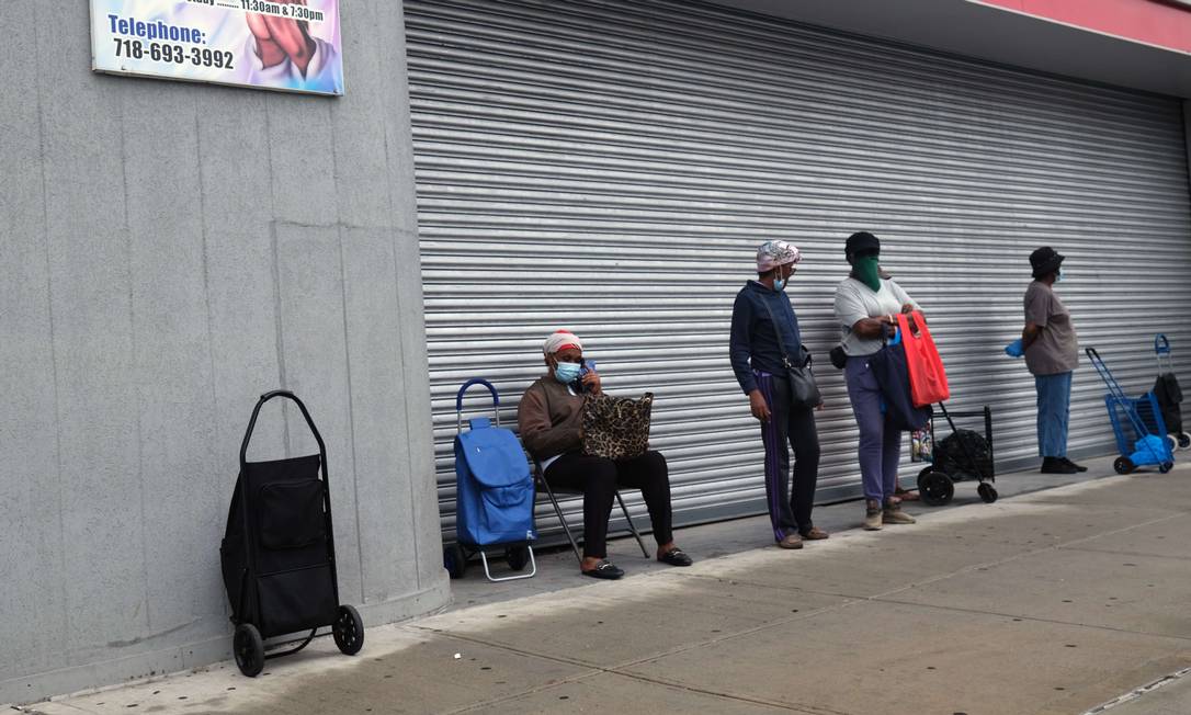 Pessoas fazem fila em um local de distribuição de comida durante a pandemia, em Nova York Foto: Spencer Platt / AFP
