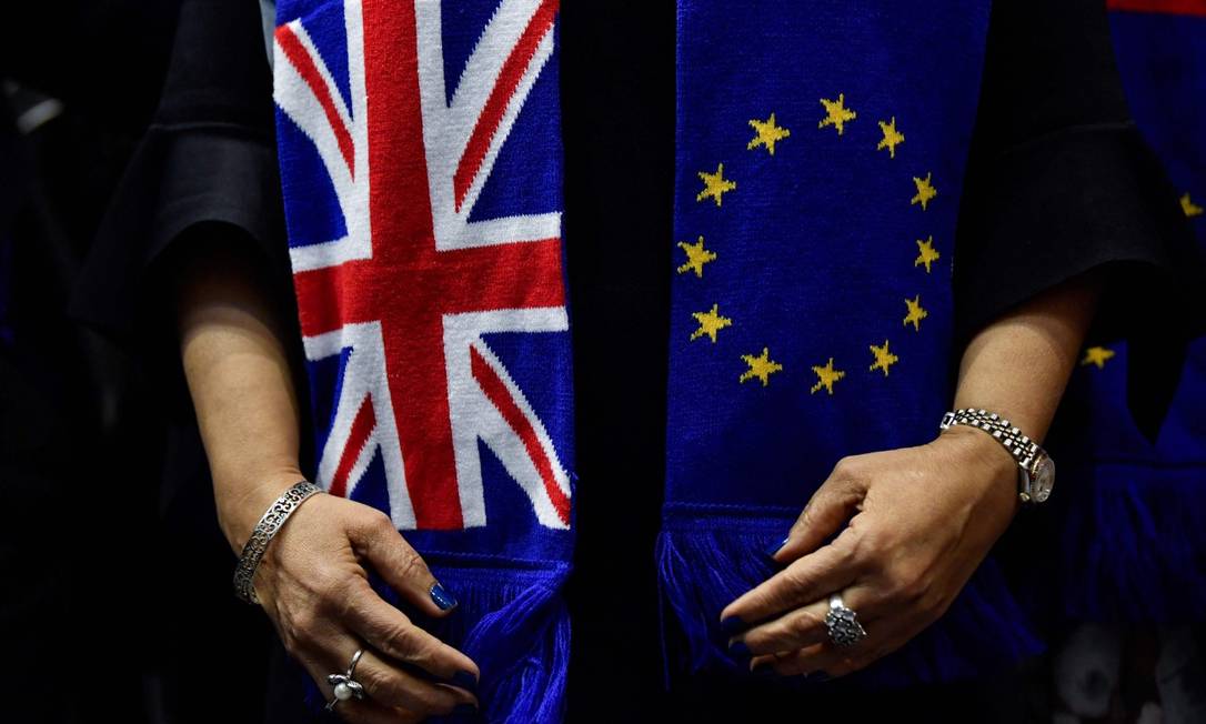 Membro do Parlamento britânico segura a Union Jack e a bandeira da UE: bloco europeu deu primeiro passo para ação legal sobre lei que viola o acordo do Brexit Foto: JOHN THYS / AFP