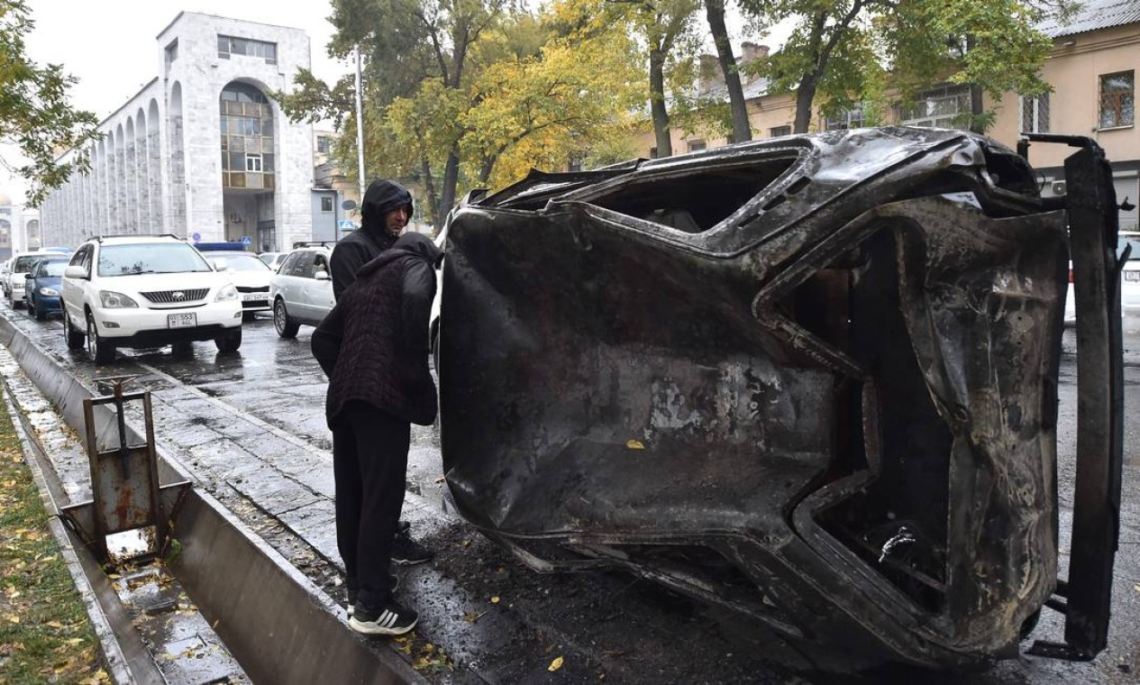 Homem olha para carro queimado em uma rua em Bisqueque Foto: VYACHESLAV OSELEDKO / AFP