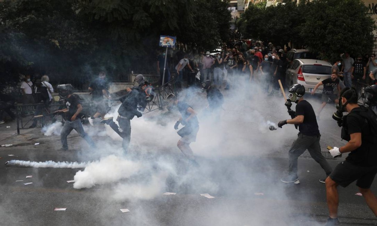 Manifestantes são vistos correndo em meio ao gás lacrimogêneo em Atenas Foto: COSTAS BALTAS / REUTERS