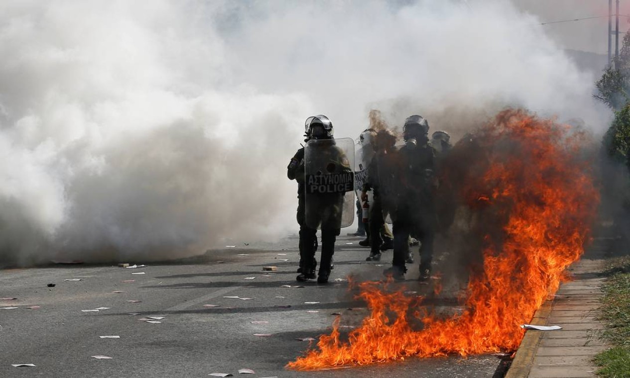 Policiais da tropa de choque são vistos entre chamas e fumaça de gás usada para dispersar manifestantes Foto: COSTAS BALTAS / REUTERS