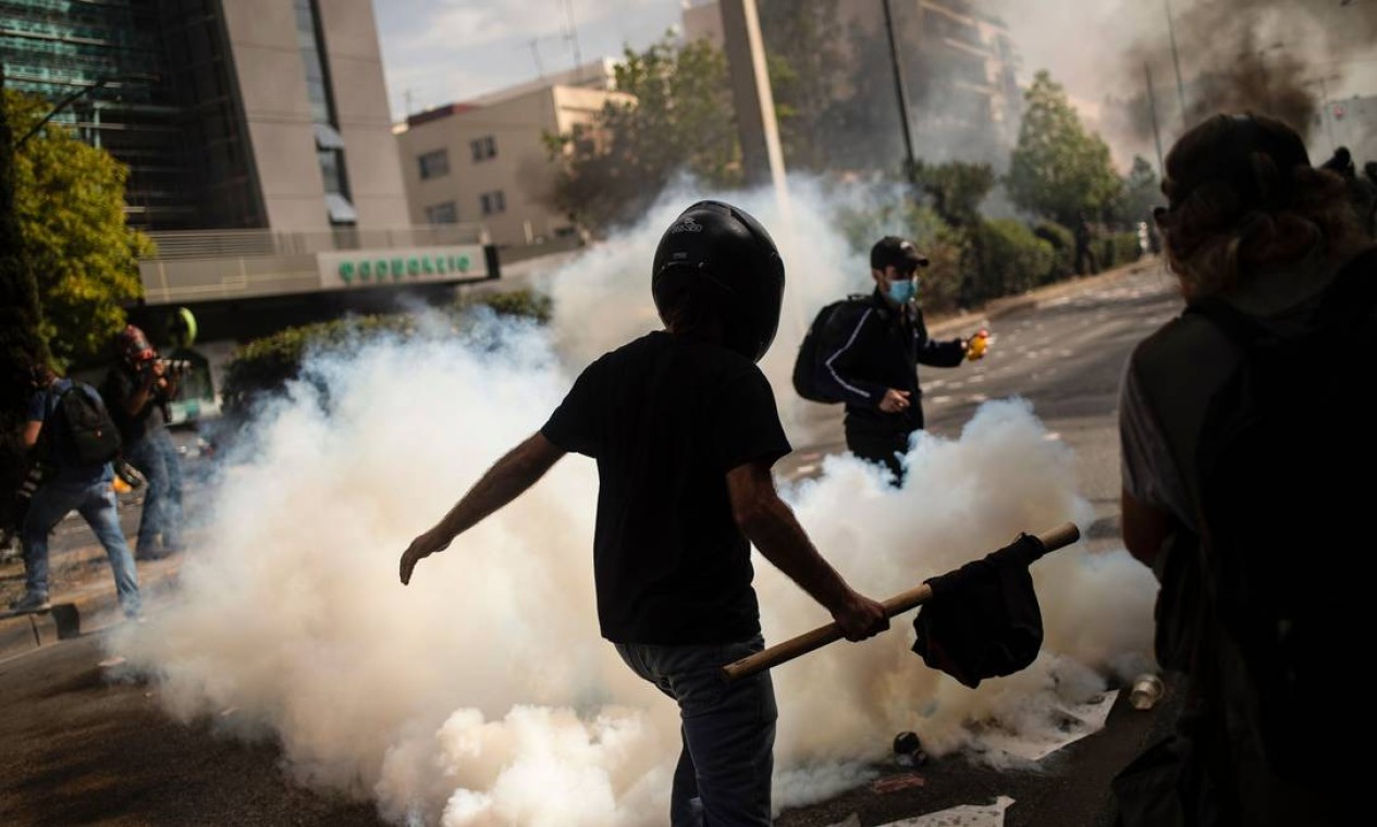 Manifestantes fogem de bomba de gás atirada pela polícia Foto: ANGELOS TZORTZINIS / AFP