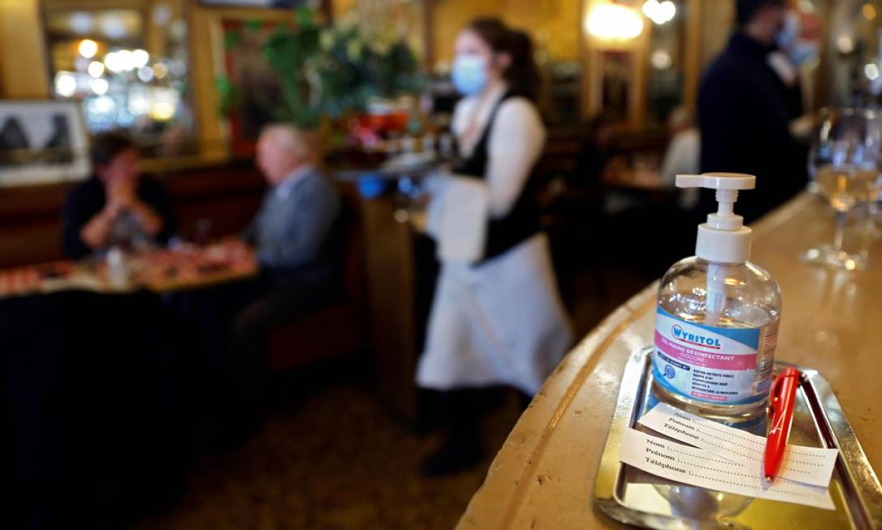 Tíquetes de registro de clientes e um frasco de gel desinfetante para as mãos são vistos em uma mesa de um restaurante em Paris às vésperas de novas medidas para combater segunda onda de Covid-19 Foto: THOMAS COEX / AFP