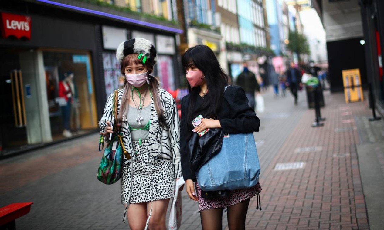 Mulheres usando máscaras passam por lojas na Oxford Street, em meio ao surto da doença coronavírus (COVID-19), em Londres Foto: HANNAH MCKAY / REUTERS